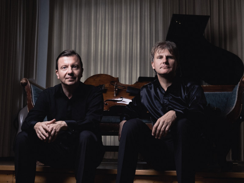 Der Pianist Evgueny Sinaisky sitzt neben dem Cellist Kirill Timofeev vor einem liegenden Cello und einem Flügel | © SINAISKI+TIMOFEEV_credits_pienavoce.org